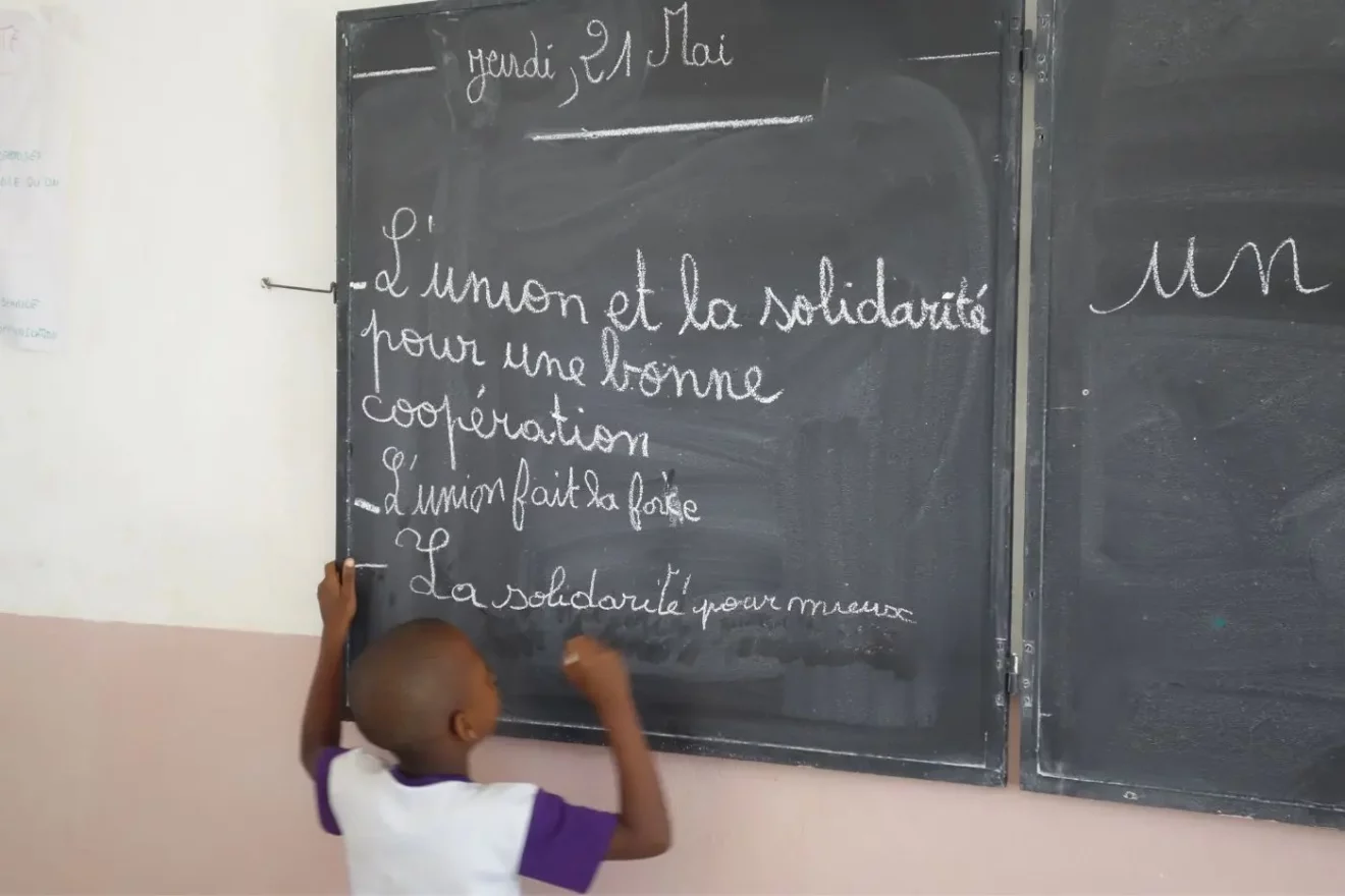 Enfant face à un tableau noir dans une classe béninoise