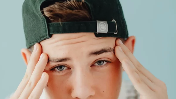 Portrait d’un adolescent, mains sur les tempes